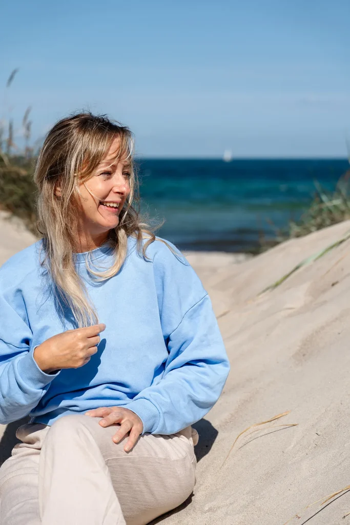 Marlen sitzt lachend in den Dünen am Meer