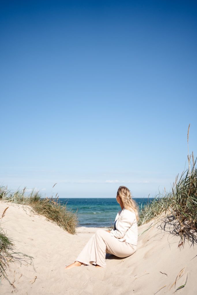 Marlen sitzt in den Dünen und blickt aufs Meer