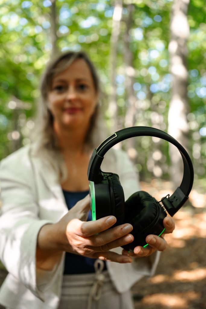 Marlen hält im Wald die Kopfhörer für eine SMT Breathwork® Session in den Händen